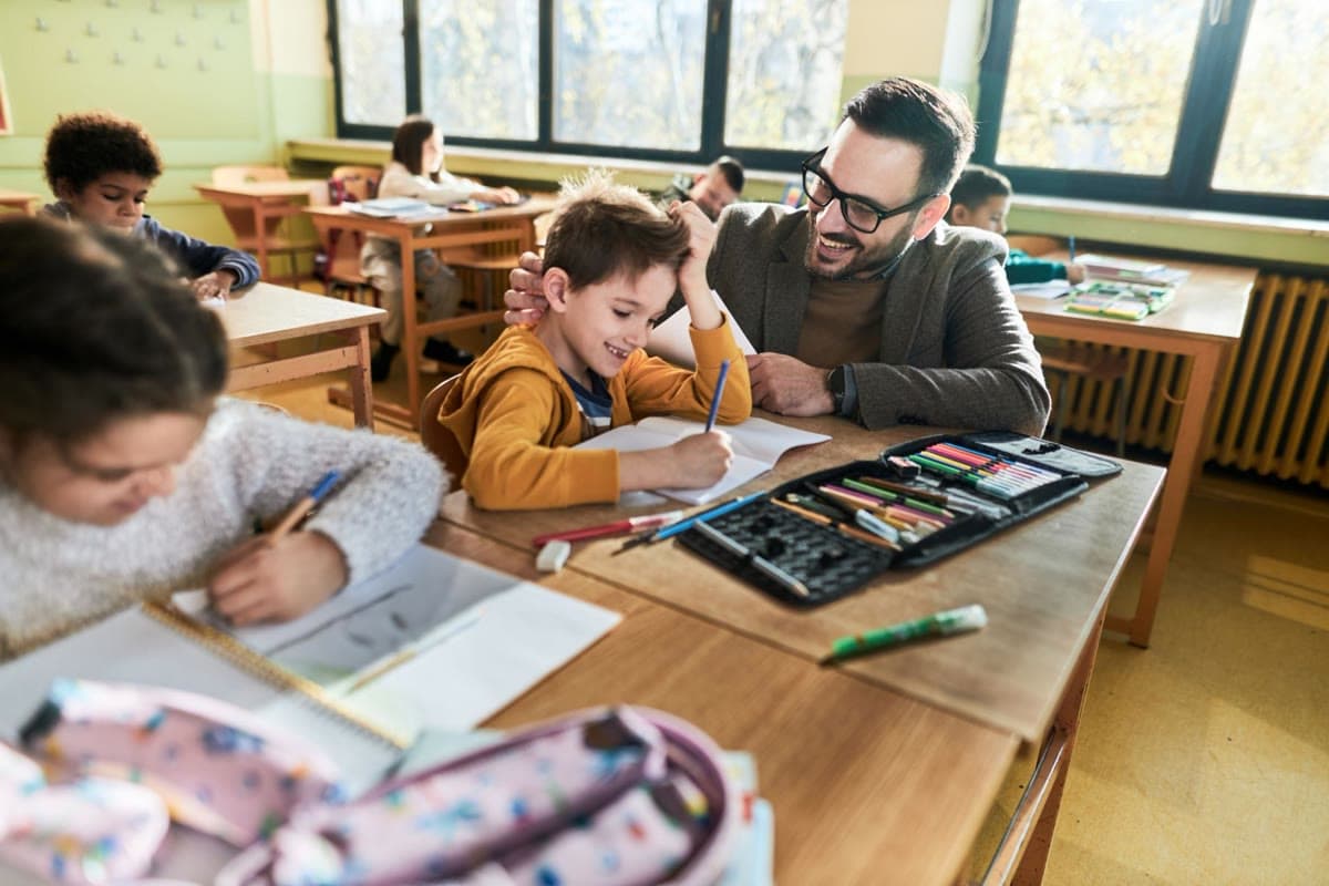 A Junior School teacher sitting with a student, helping with their work