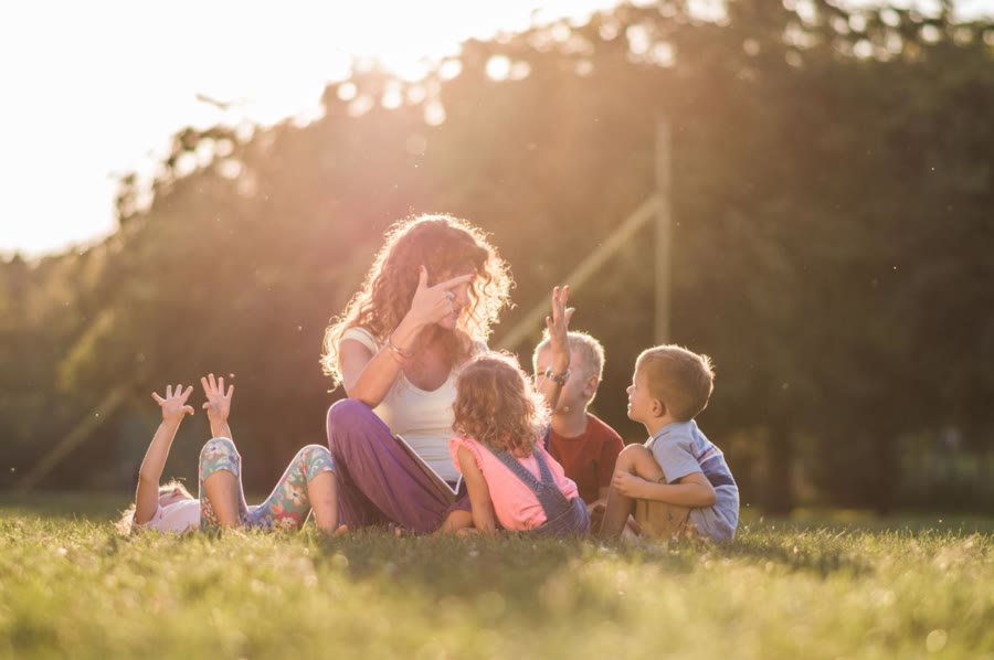 A teacher reading with students outdoors in the evening light