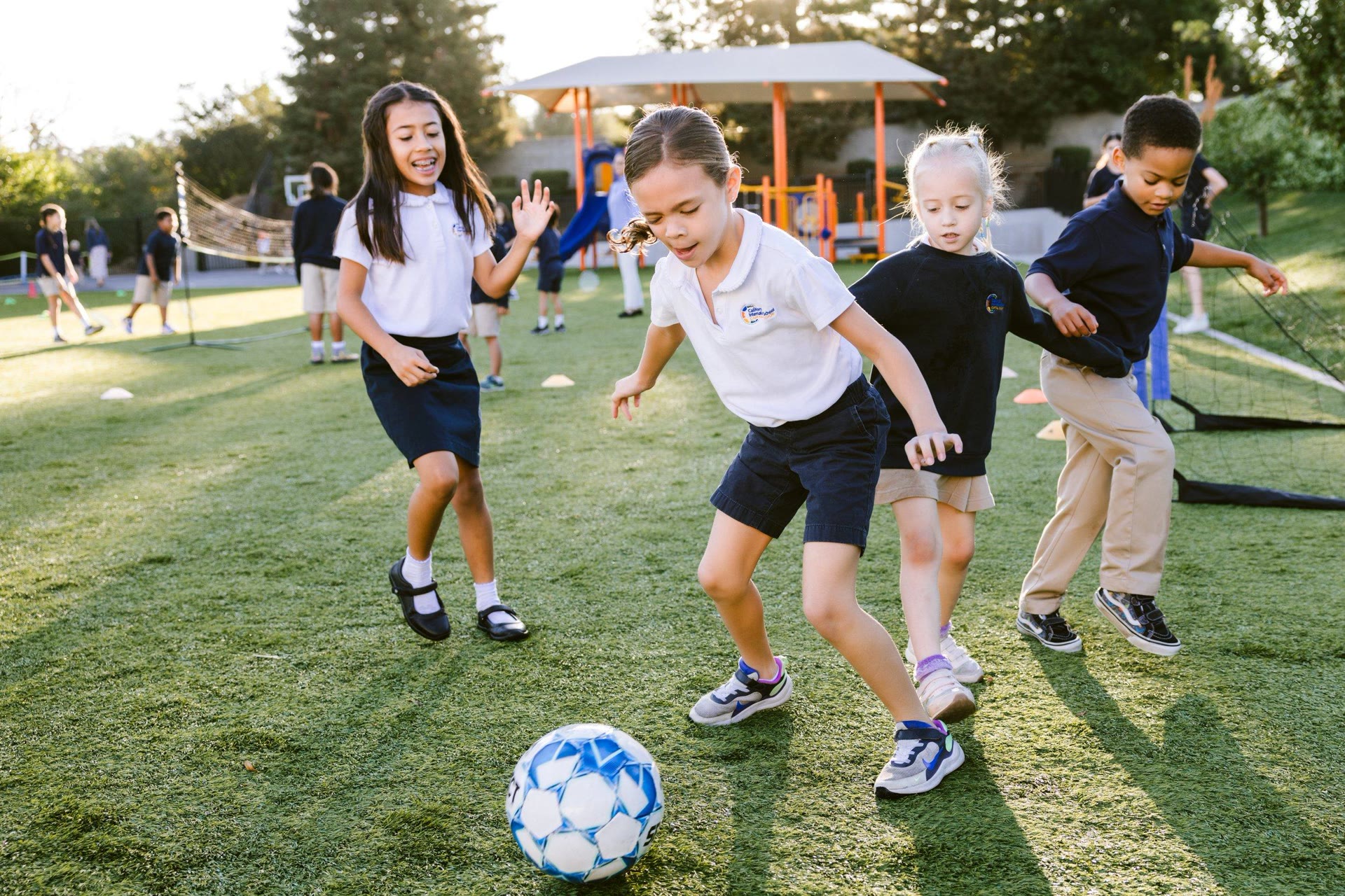 Junior School students playing football together on the field