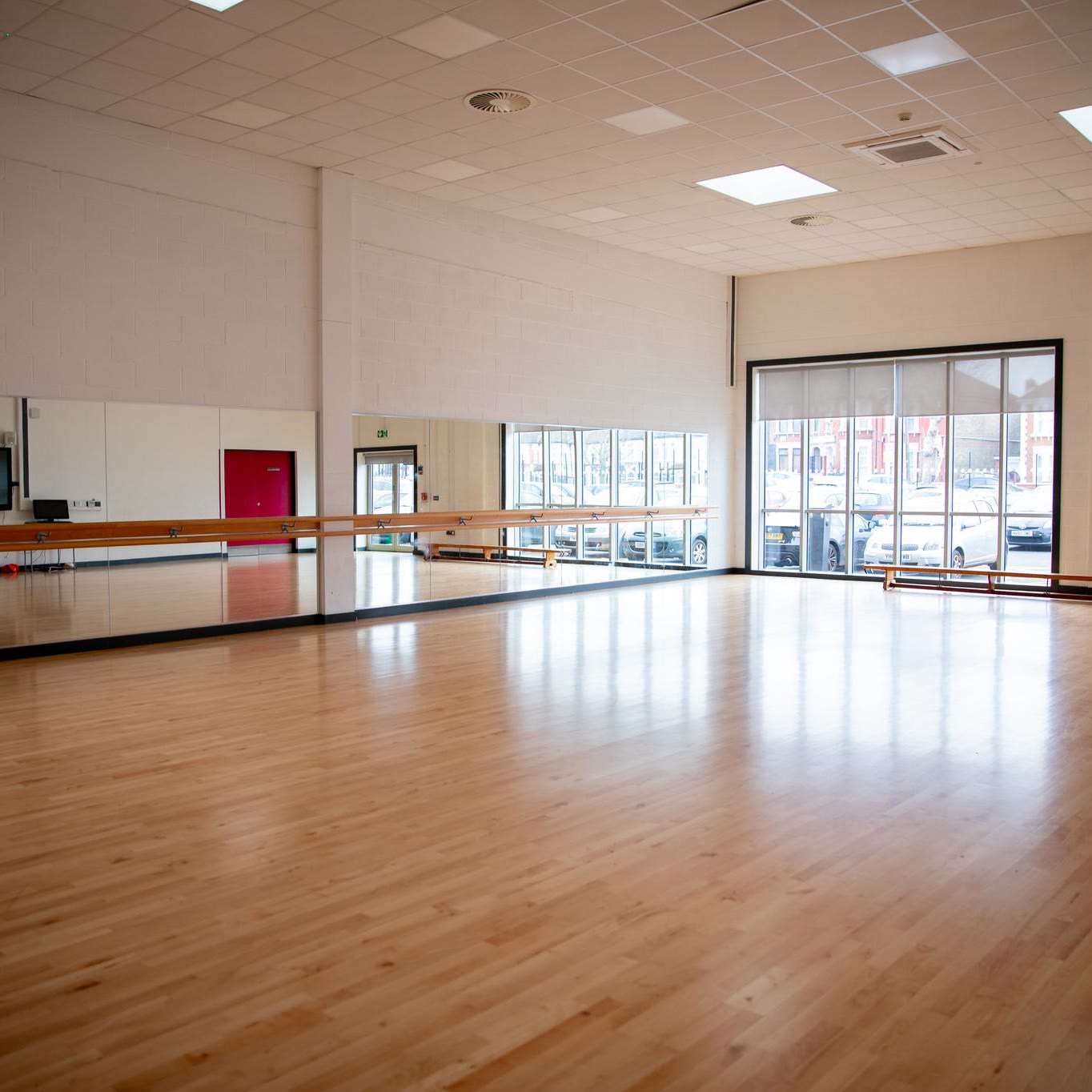 An empty dance studio with a mirrored wall and barre